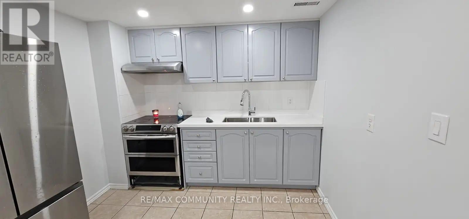A kitchen with a stainless steel refrigerator and a stove top oven.