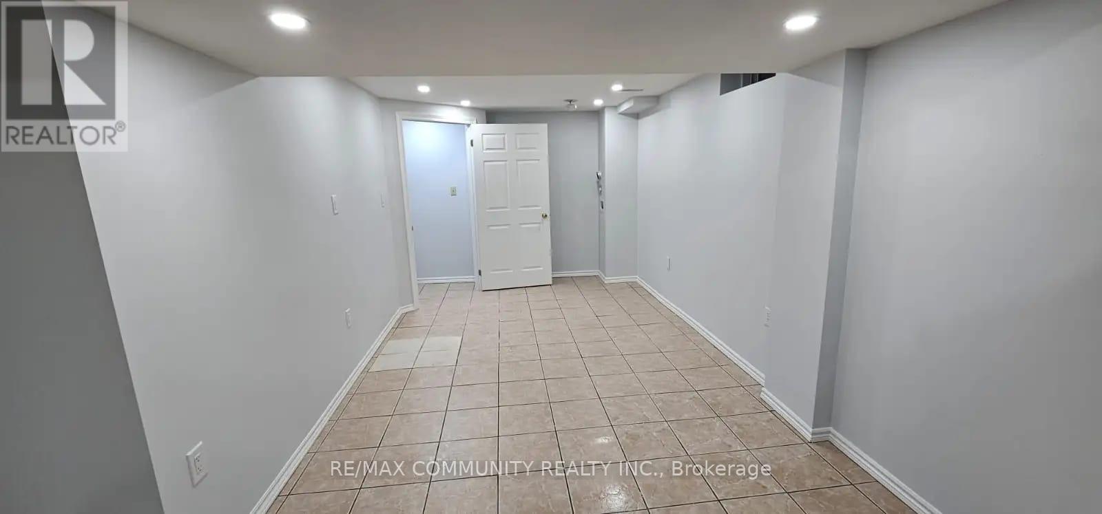 A spacious room with tiled flooring and white walls, with a door at the end.