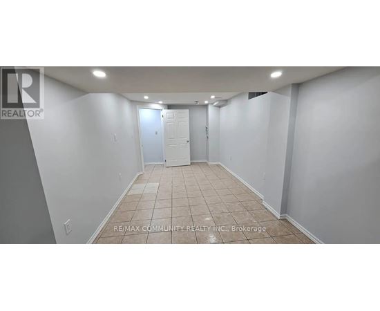 A spacious room with tiled flooring and white walls, with a door at the end.