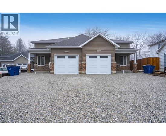 A house with a gravel driveway and two garages is for sale.