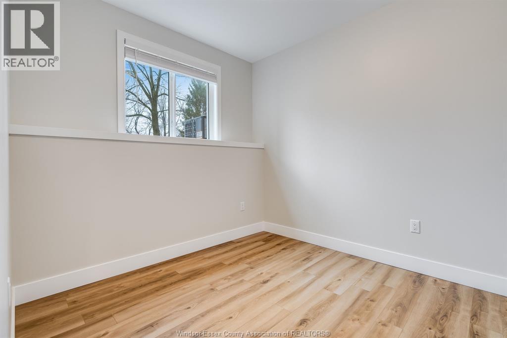 A room with wooden flooring and a window showing trees outside.