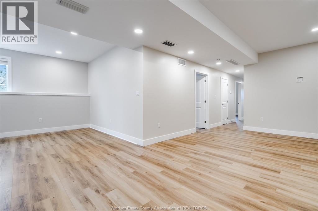 A spacious room with wooden flooring and white walls.