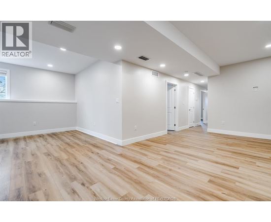 A spacious room with wooden flooring and white walls.