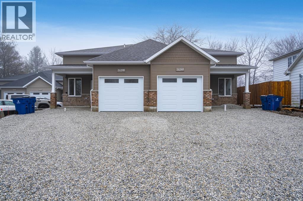 A house with a gravel driveway and two garages is for sale.