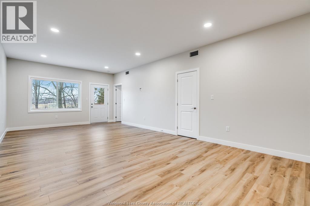 A spacious room with wooden flooring and white walls.