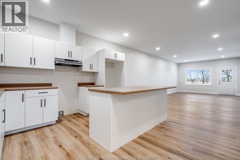 A spacious kitchen with white cabinets and wooden flooring.