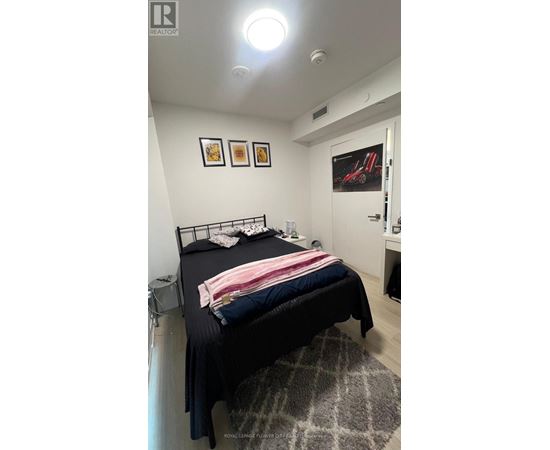 A bedroom with a bed, a rug, and pictures on the wall.