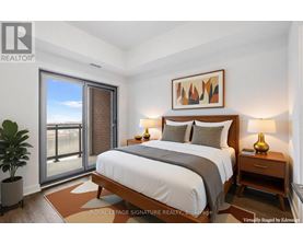 A bedroom with a large bed, a potted plant, and a painting on the wall.