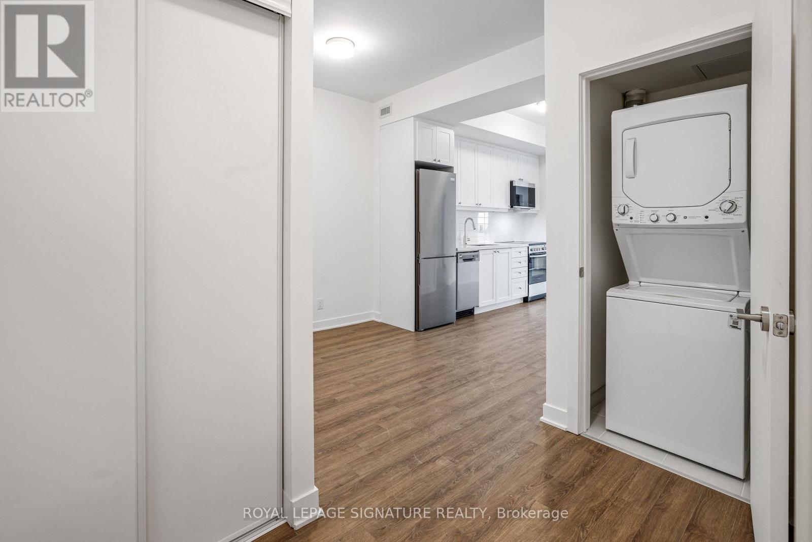 A white door is open to a kitchen with a fridge and a microwave.