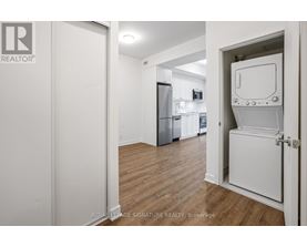 A white door is open to a kitchen with a fridge and a microwave.