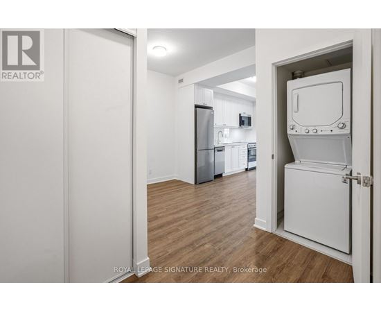 A white door is open to a kitchen with a fridge and a microwave.