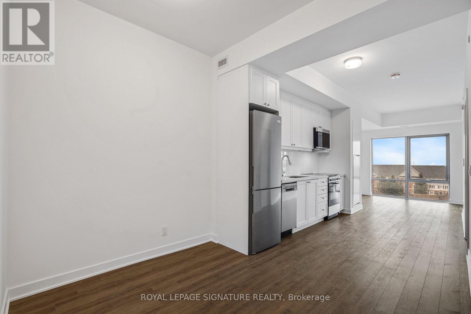 A well-lit, spacious kitchen with white cabinets and a stainless steel refrigerator.