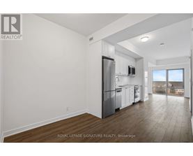 A well-lit, spacious kitchen with white cabinets and a stainless steel refrigerator.