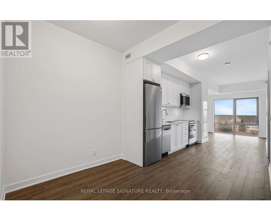 A well-lit, spacious kitchen with white cabinets and a stainless steel refrigerator.