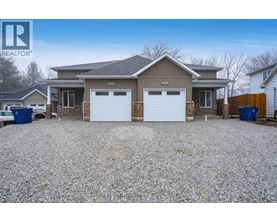 A house with a gravel driveway and two garages is for sale.