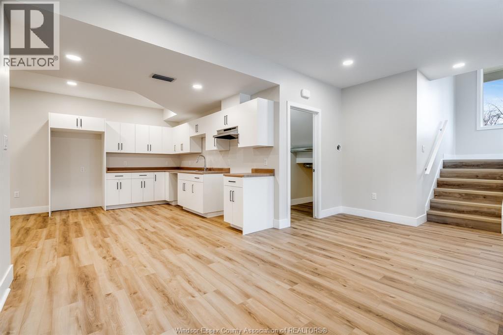 A spacious kitchen with white cabinets and wooden flooring.