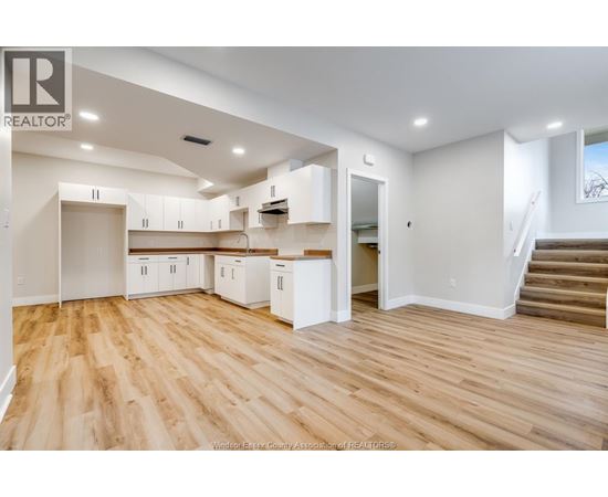 A spacious kitchen with white cabinets and wooden flooring.