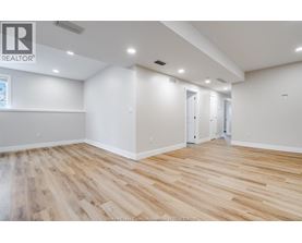 A spacious room with wooden flooring and white walls.