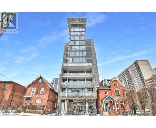 A tall building with a glass facade stands in front of a row of older brick houses.