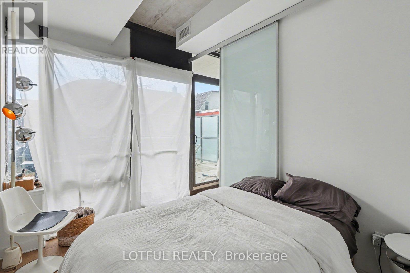 A bedroom with a large bed and a chair.