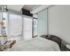A bedroom with a large bed and a chair.