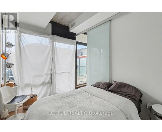 A bedroom with a large bed and a chair.