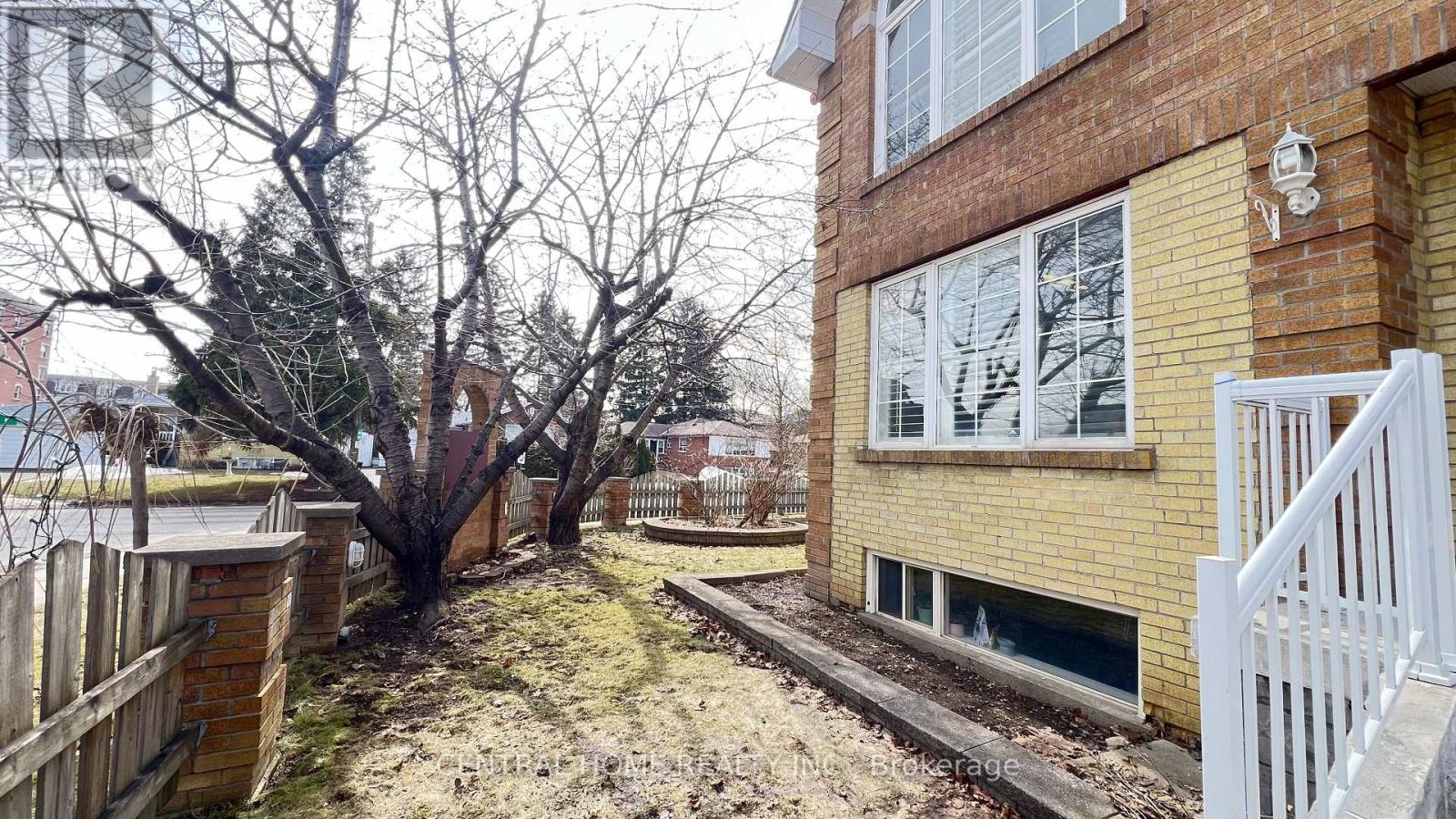 A small tree is in front of a brick building.