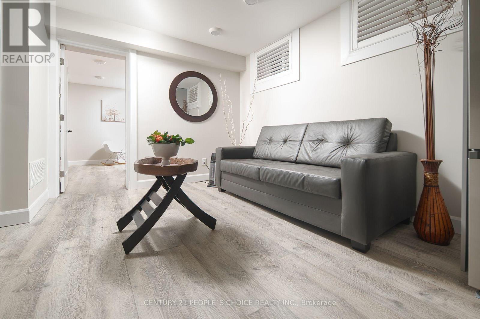 A living room with a grey couch, a wooden table, and a vase with a plant.