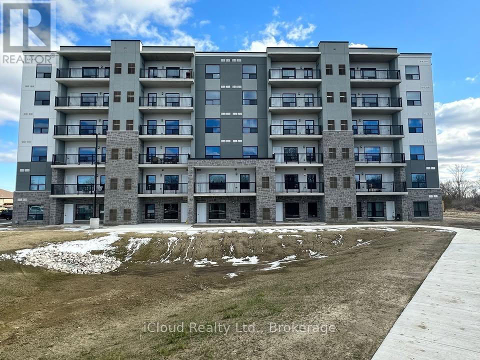 A large apartment building with a grassy area in front and a road leading to the entrance.