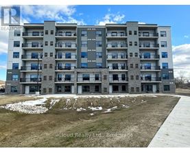 A large apartment building with a grassy area in front and a road leading to the entrance.