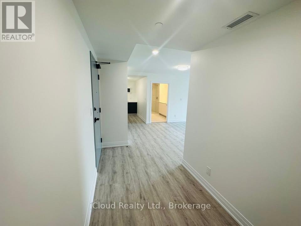 A hallway with wood flooring and white walls.