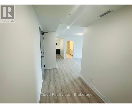 A hallway with wood flooring and white walls.