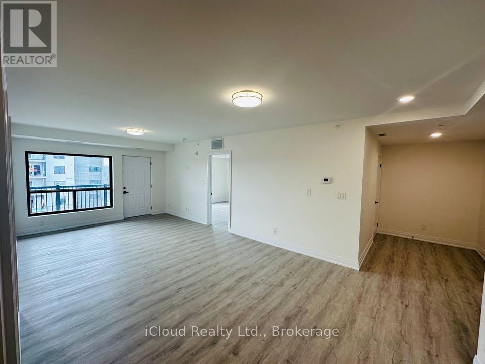 A spacious room with wooden flooring and white walls, with a window and a door visible.