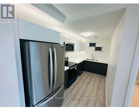 A modern kitchen with a stainless steel refrigerator and wooden flooring.