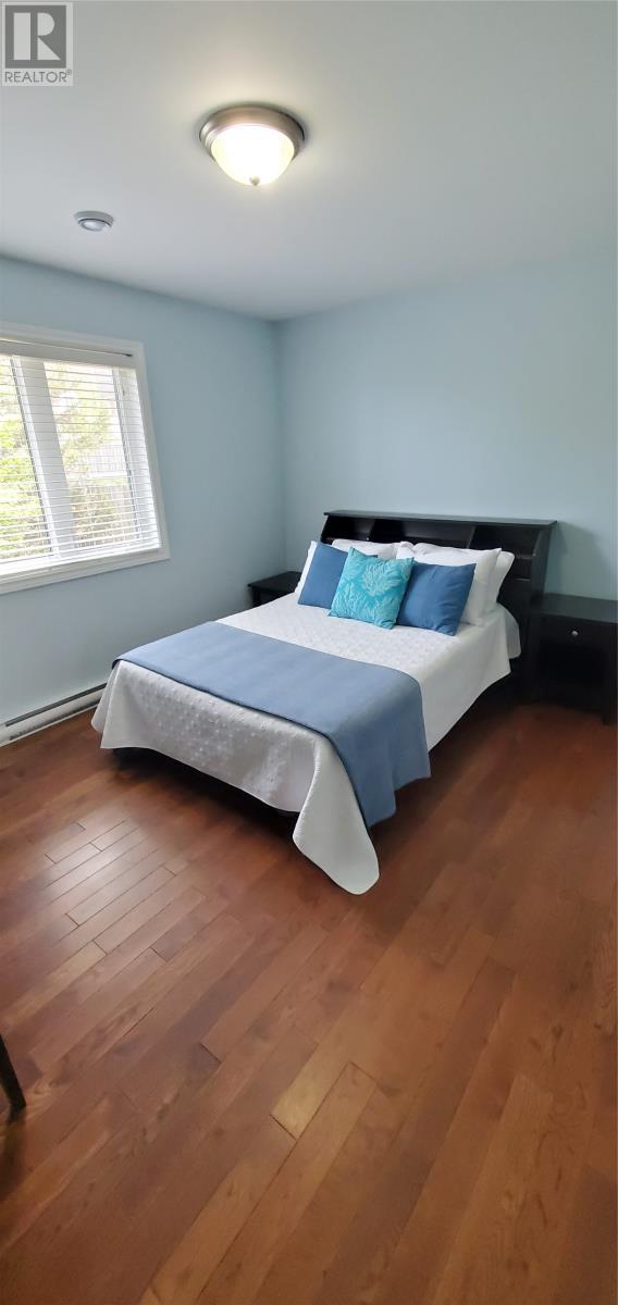 A bedroom with a bed and wooden floors.