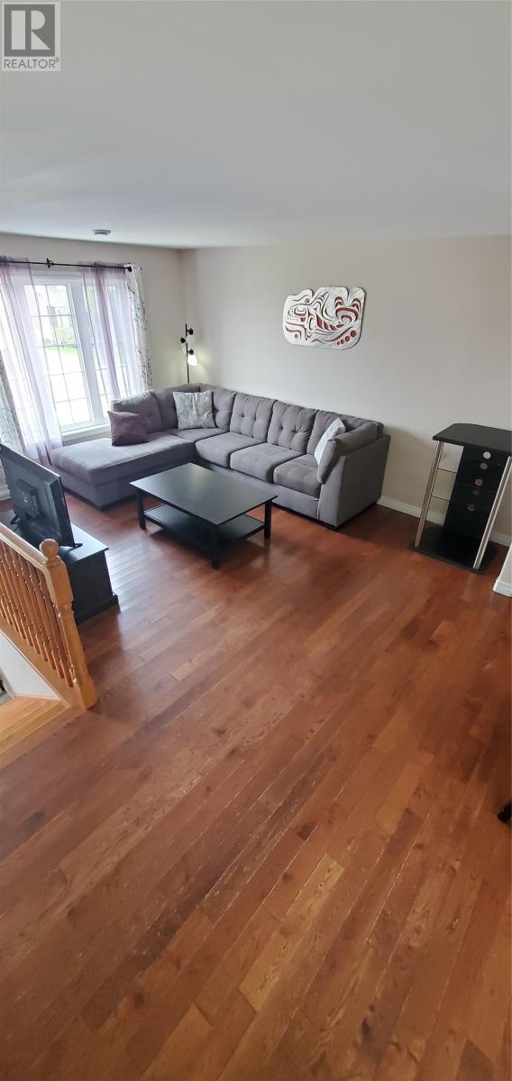 A living room with a grey couch and a wooden floor.