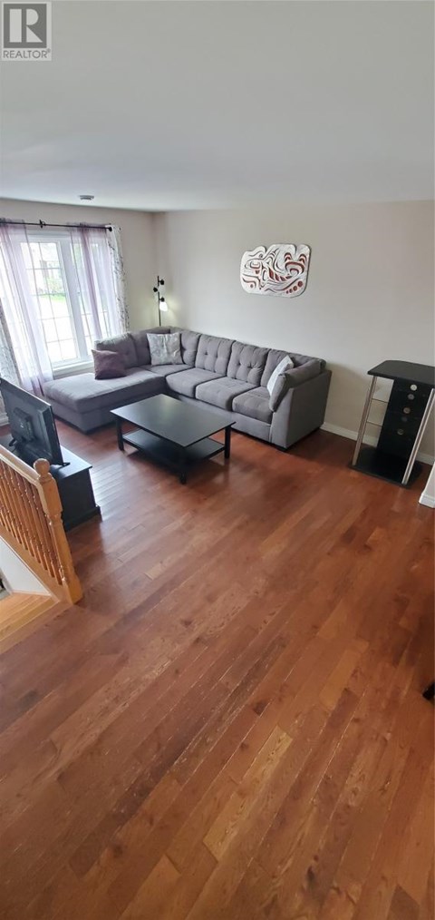 A living room with a grey couch and a wooden floor.