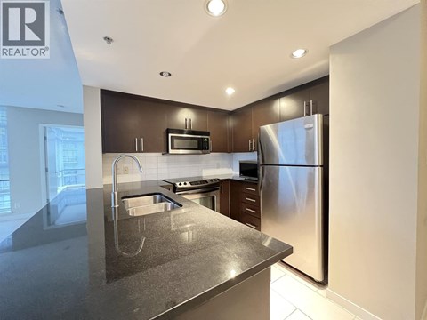 A modern kitchen with a stainless steel refrigerator and microwave.