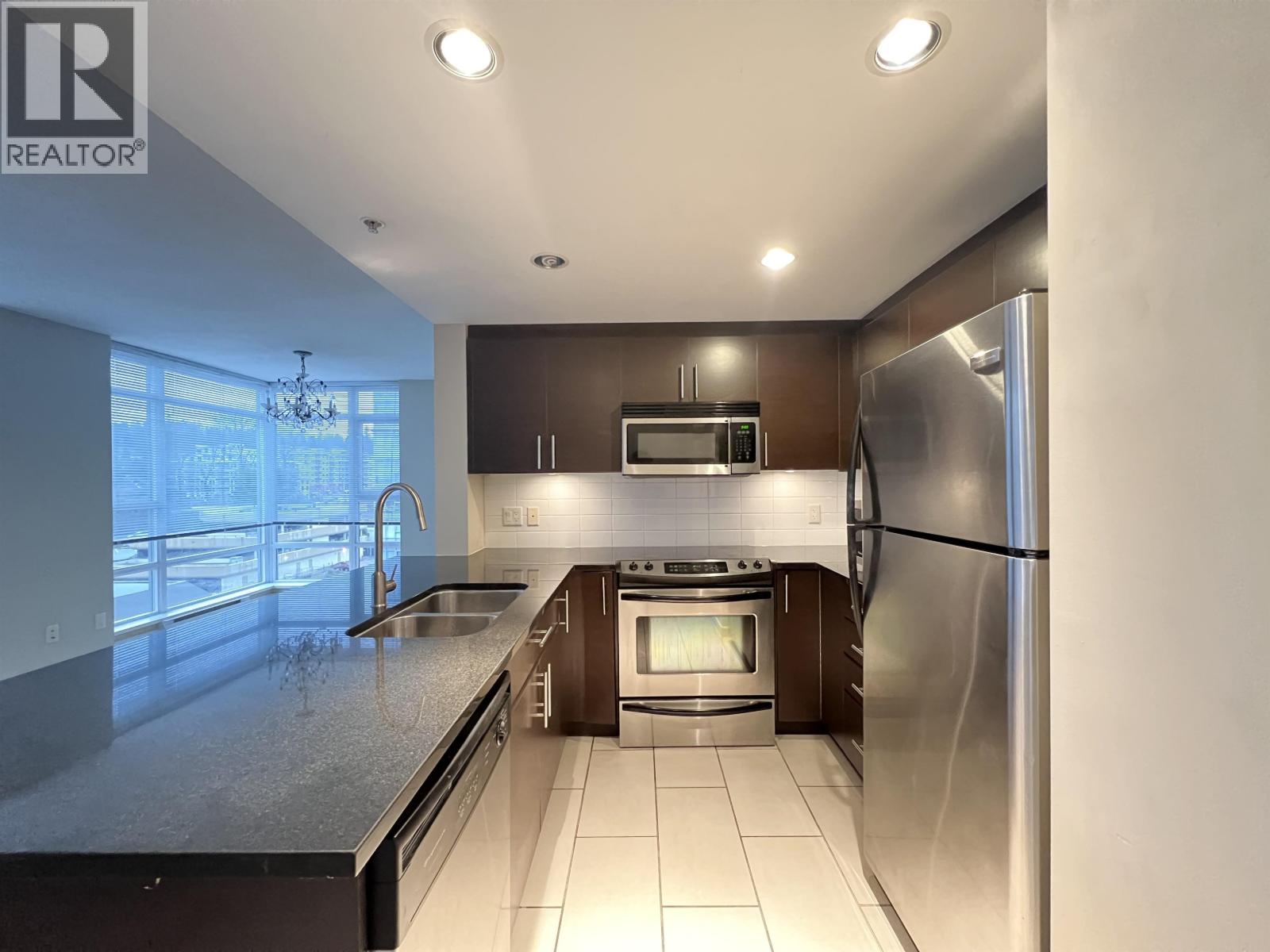 A modern kitchen with stainless steel appliances and a large island.