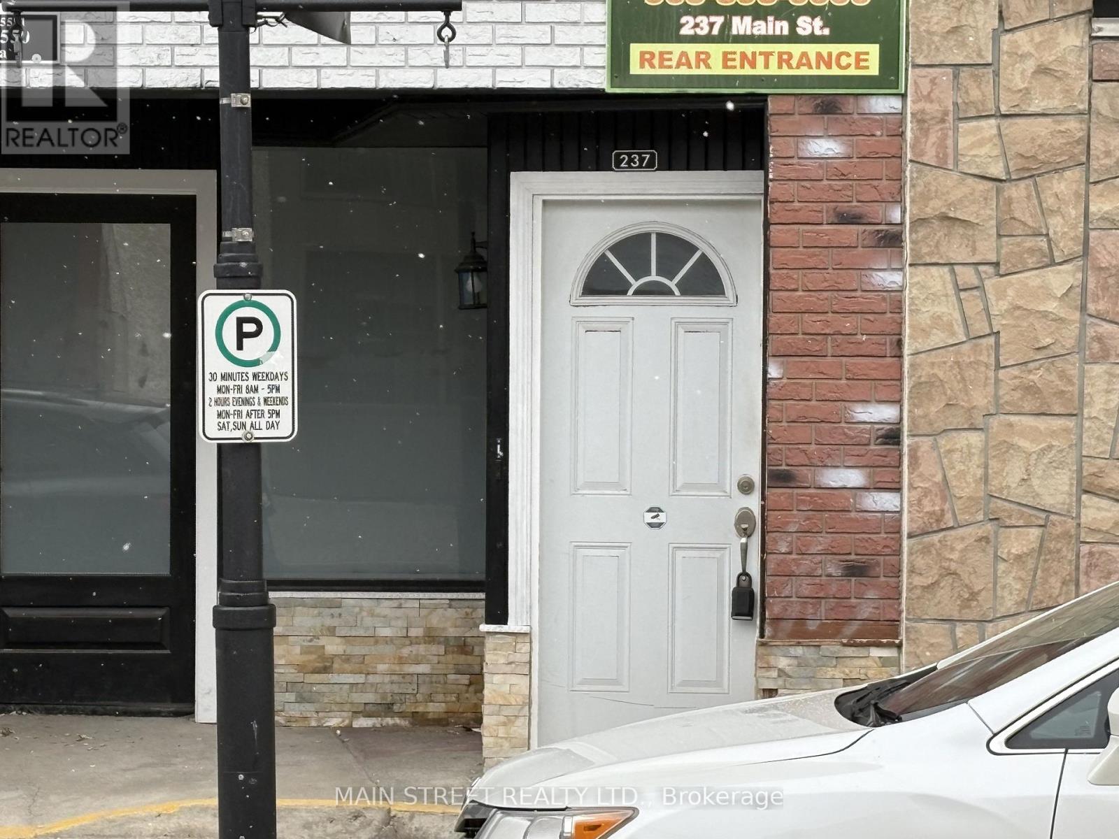 A parking sign is posted on a pole in front of a building.