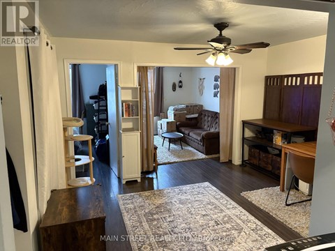 A living room with a rug on the floor and a ceiling fan above.
