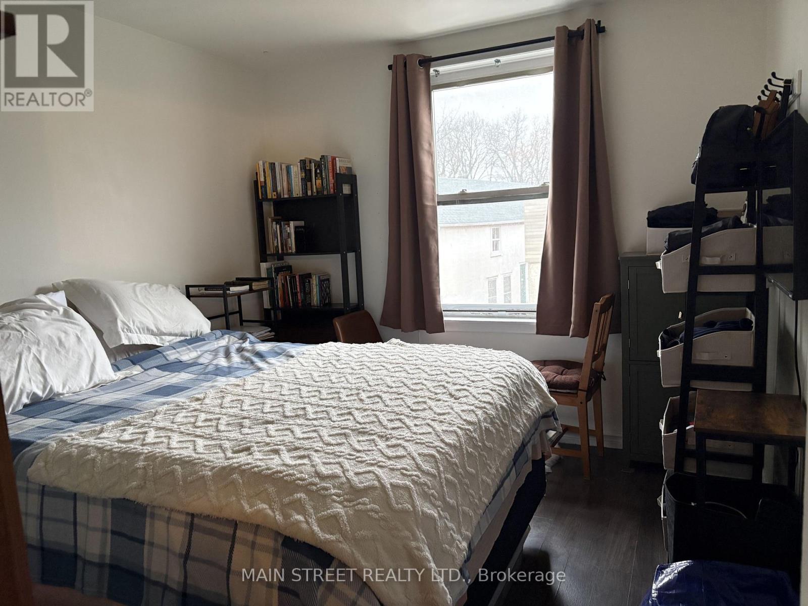 A bedroom with a bed, a chair, and a window with curtains.