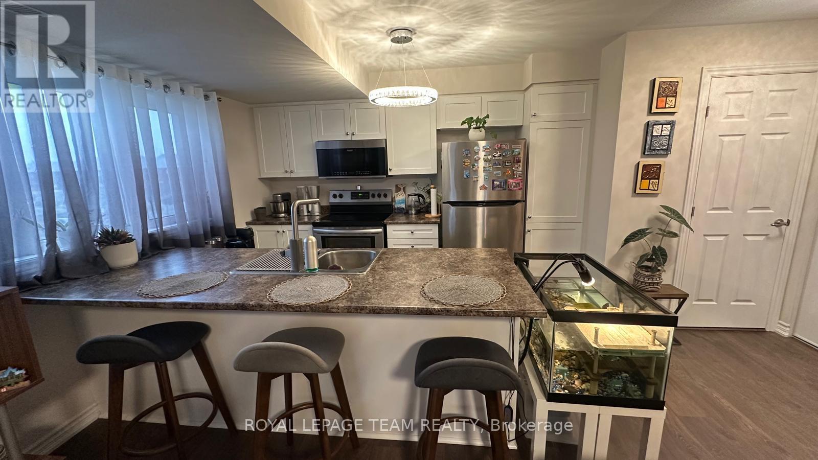 A kitchen with a refrigerator, stove, and bar stools.