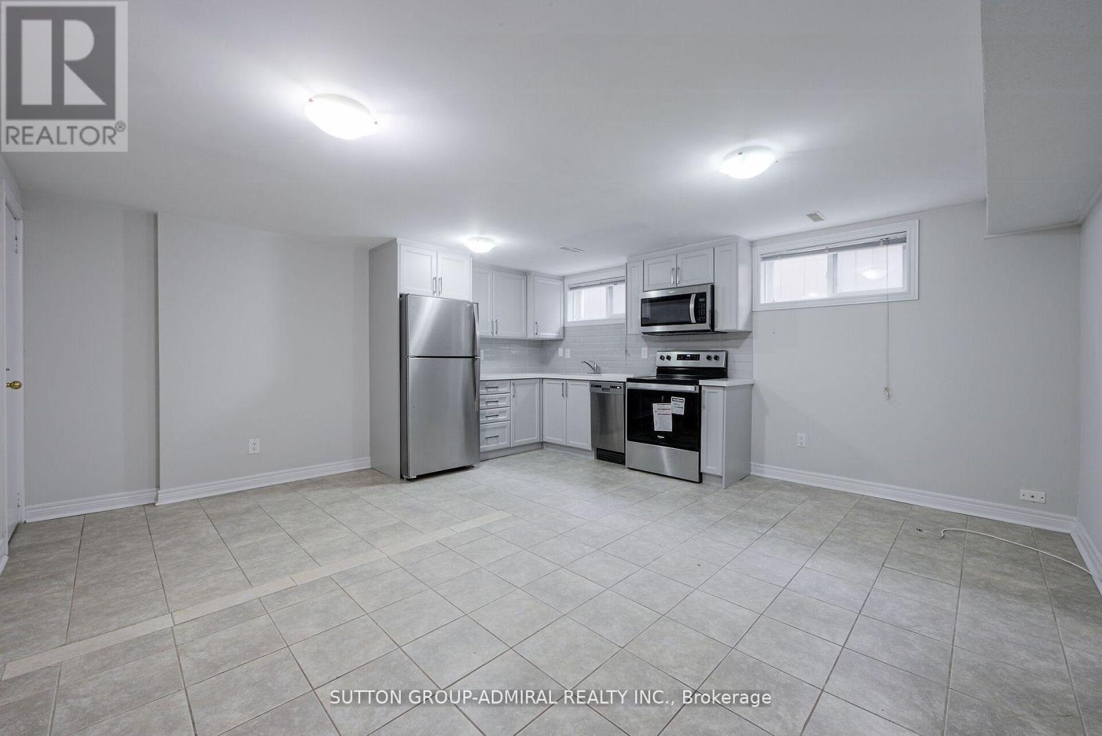 A spacious kitchen with white cabinets and appliances in a room with a tiled floor.