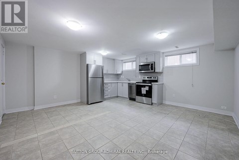 A spacious kitchen with white cabinets and appliances in a room with a tiled floor.