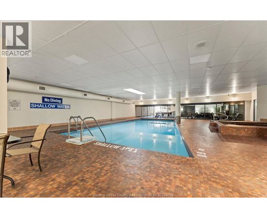 A large indoor swimming pool with a no diving shallow water sign.