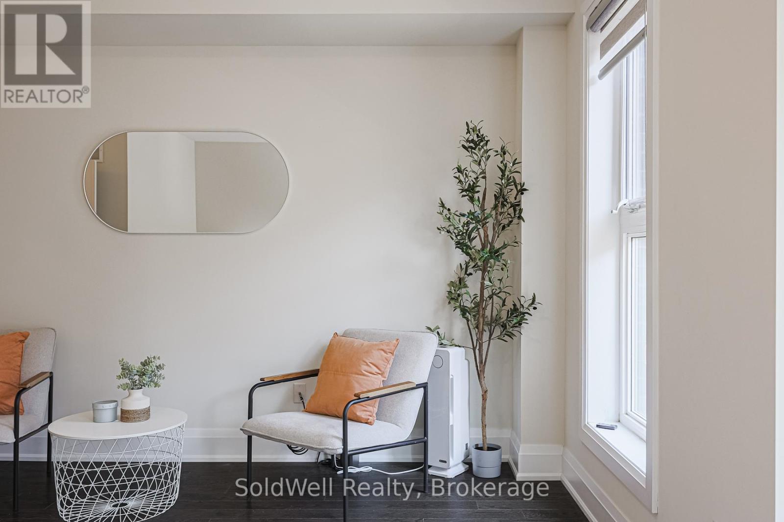 A living room with a white chair and a small table with a plant on it.