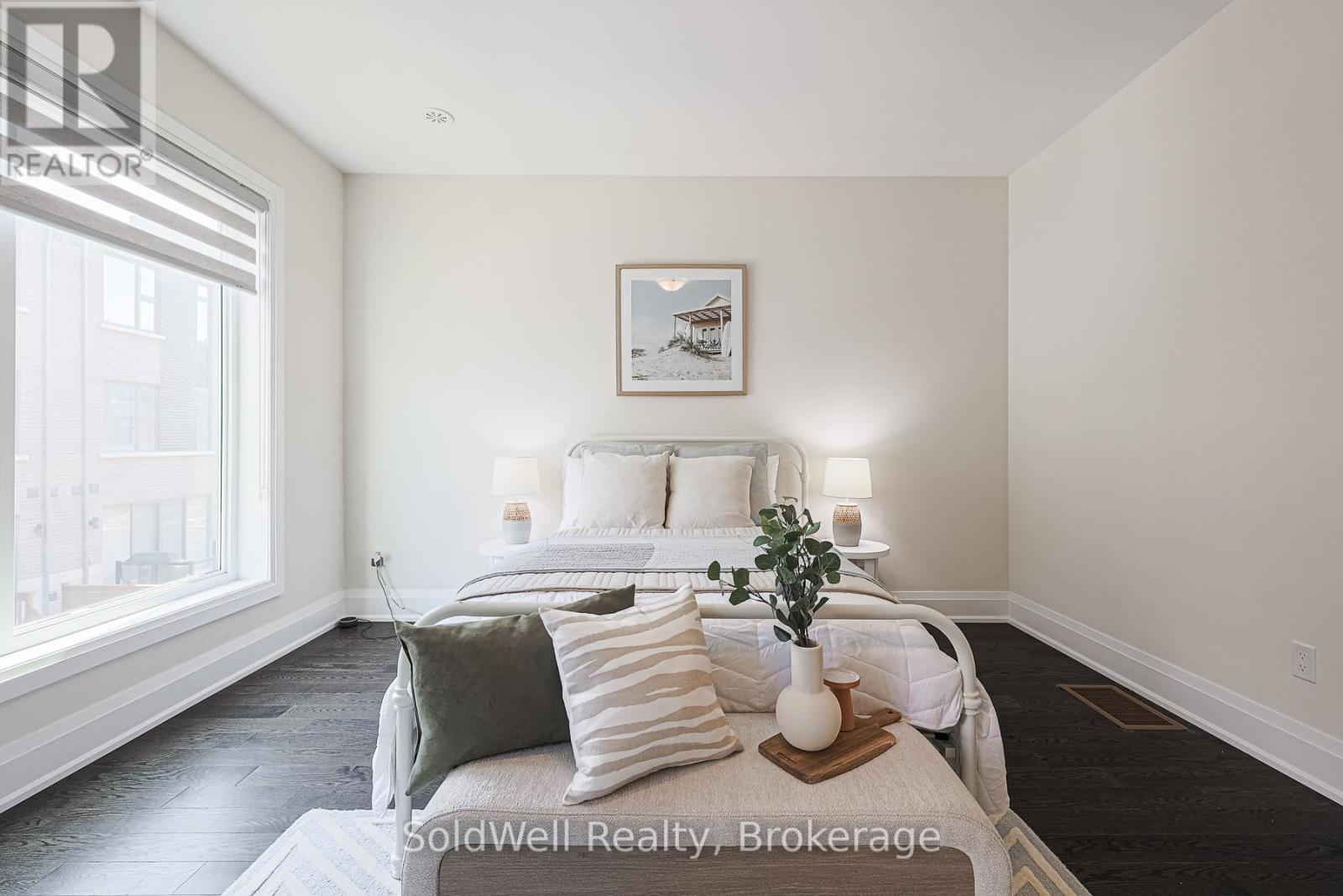 A bedroom with a large bed and a picture on the wall.