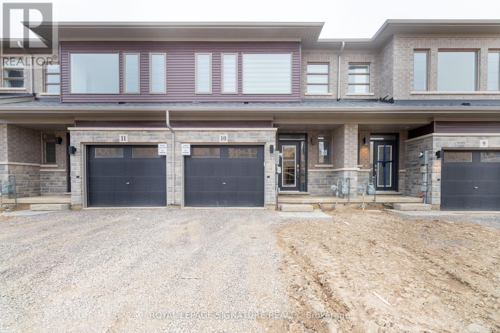 A large, multi-level residential building with a gravel driveway in front.