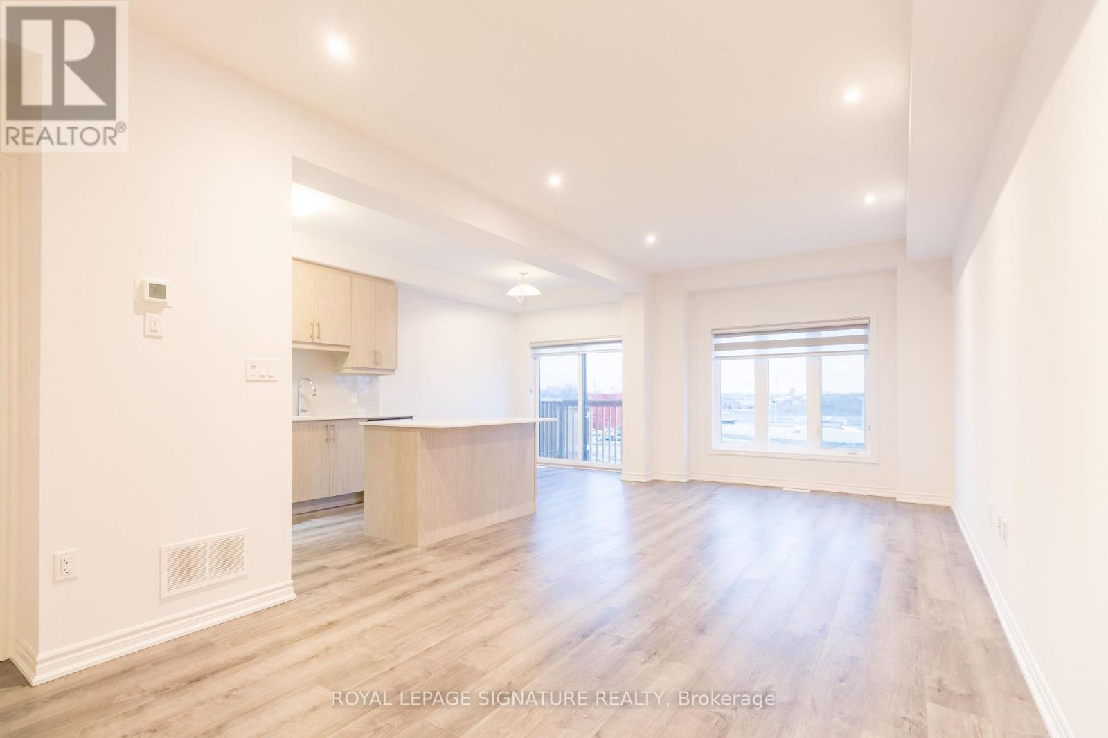 A spacious room with wooden flooring and white walls.